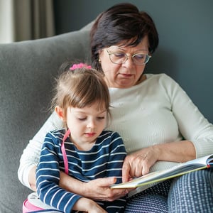 A grandmother reads a picture book with her granddaughter